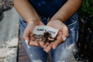 A woman holds change with a note saying "make a change"