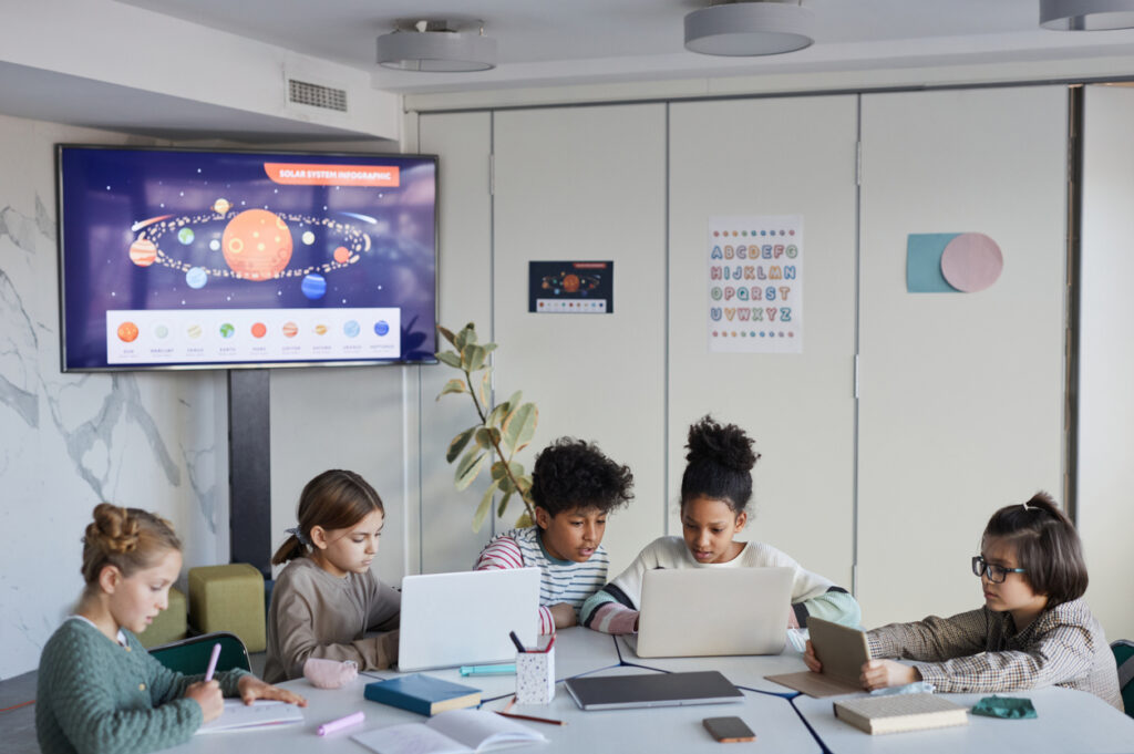 Diverse group of children at table in modern school